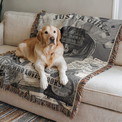 A golden retriever dog is lying on a couch with a blanket that has a book-themed design.
