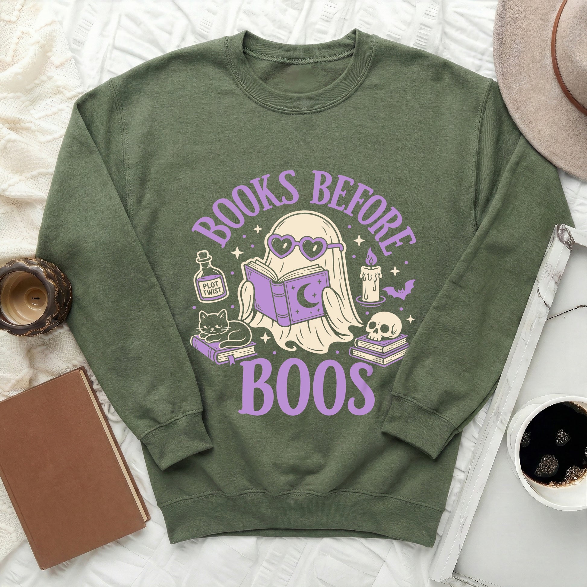 Green sweatshirt with graphic of ghost reading, cat, and skull, says "Books Before Boos".