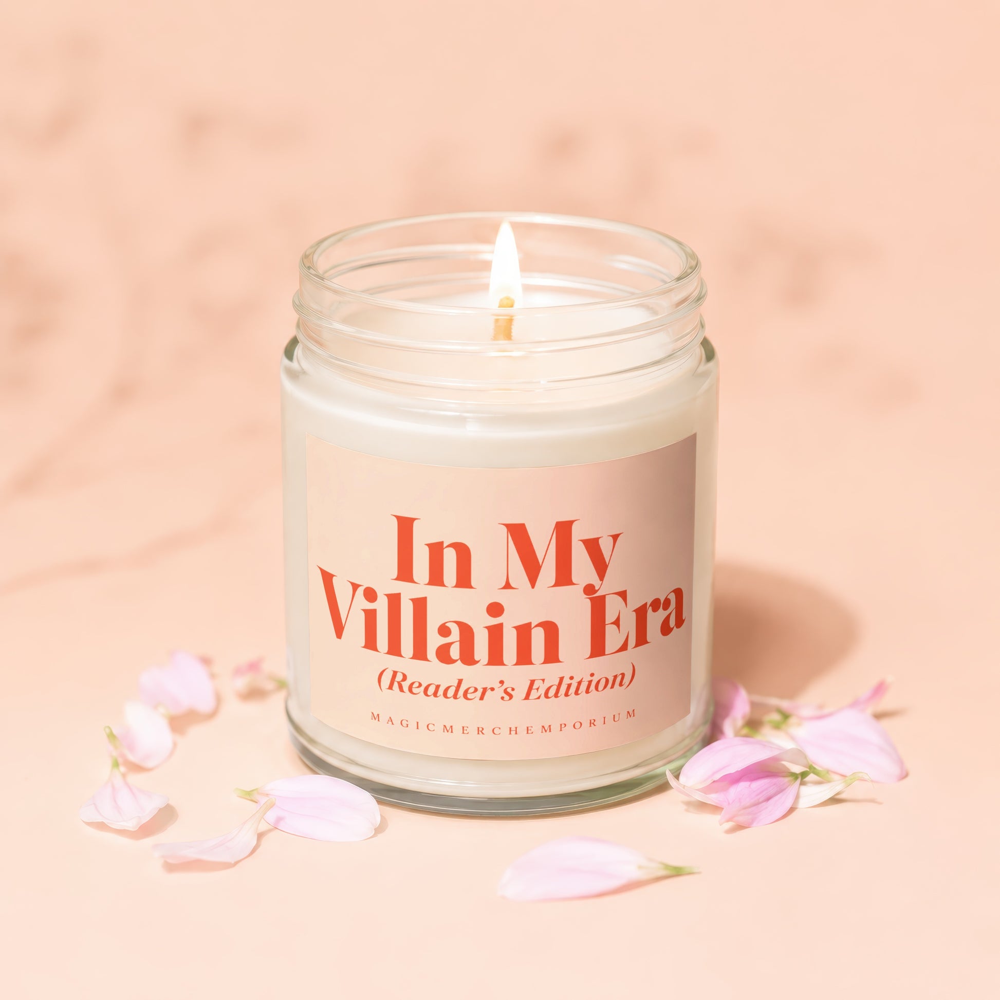 Lit candle in glass jar with pink label reading "In My Villain Era (Reader's Edition)".