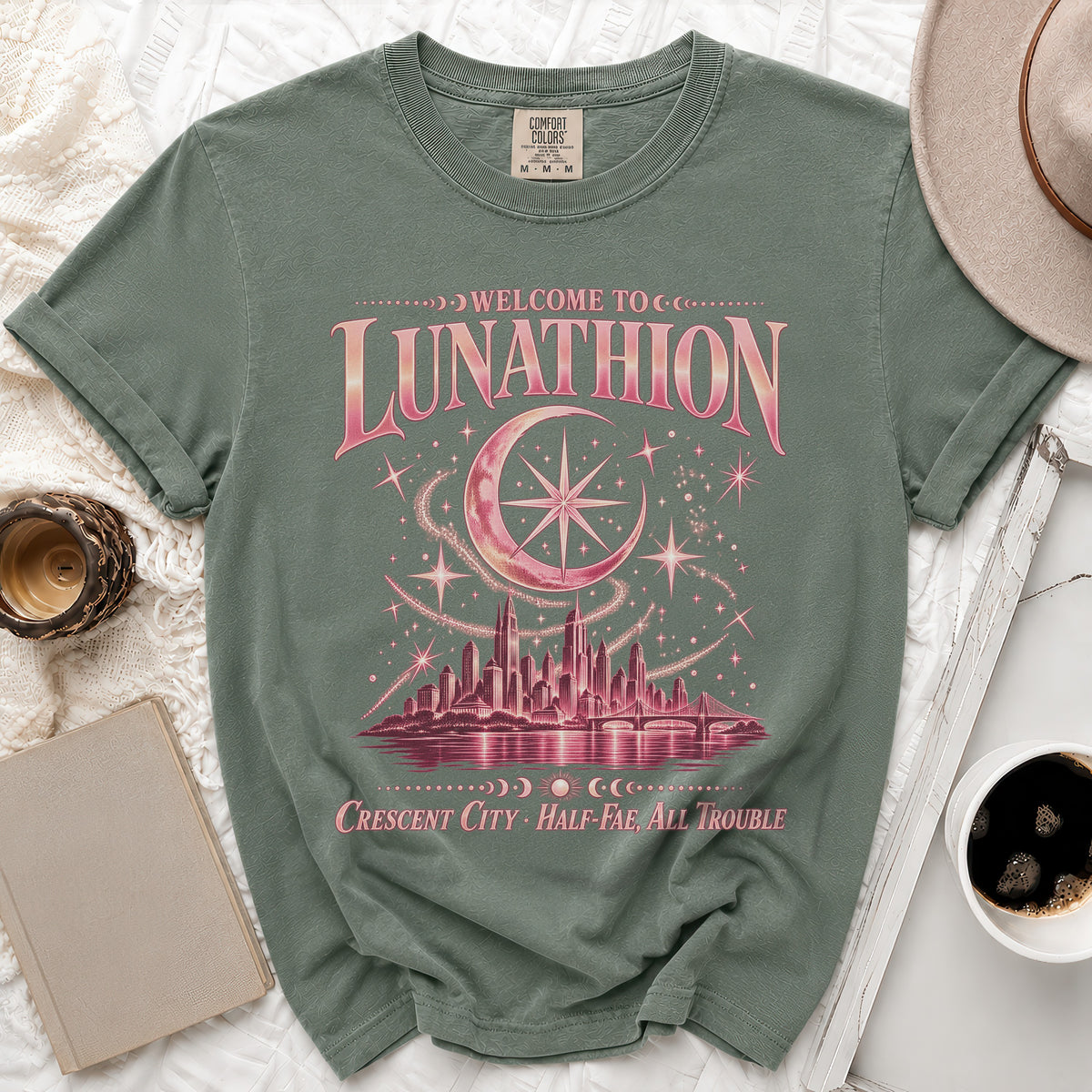 Green t-shirt with "Welcome to Lunathion Crescent City Half-Fae, All Trouble" text and celestial design.