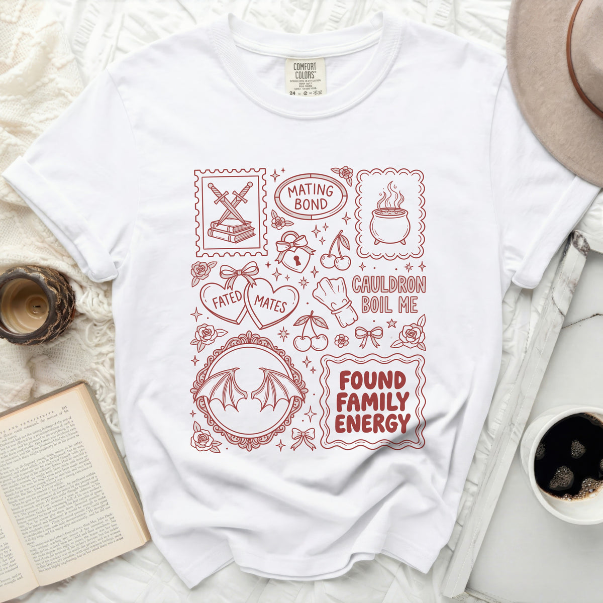 White t-shirt with red outline illustrations of bats wings, cherries, cauldron, hearts, and text.