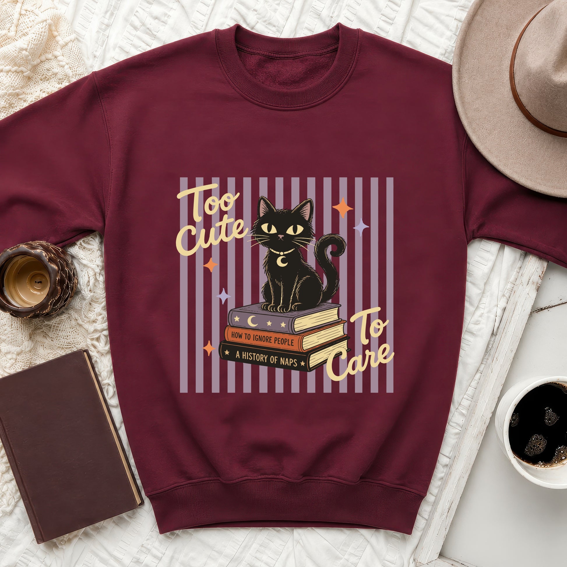 Maroon sweatshirt with black cat on books graphic text Too Cute To Care