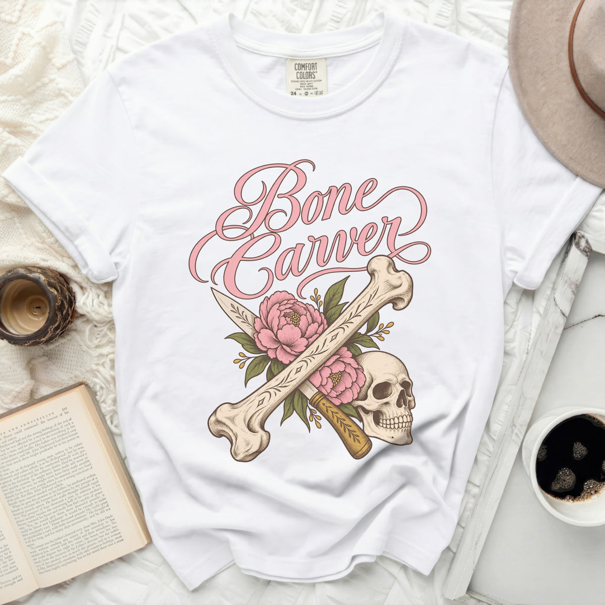 White t-shirt with pink "Bone Carver" text, skull, bones, and flowers.