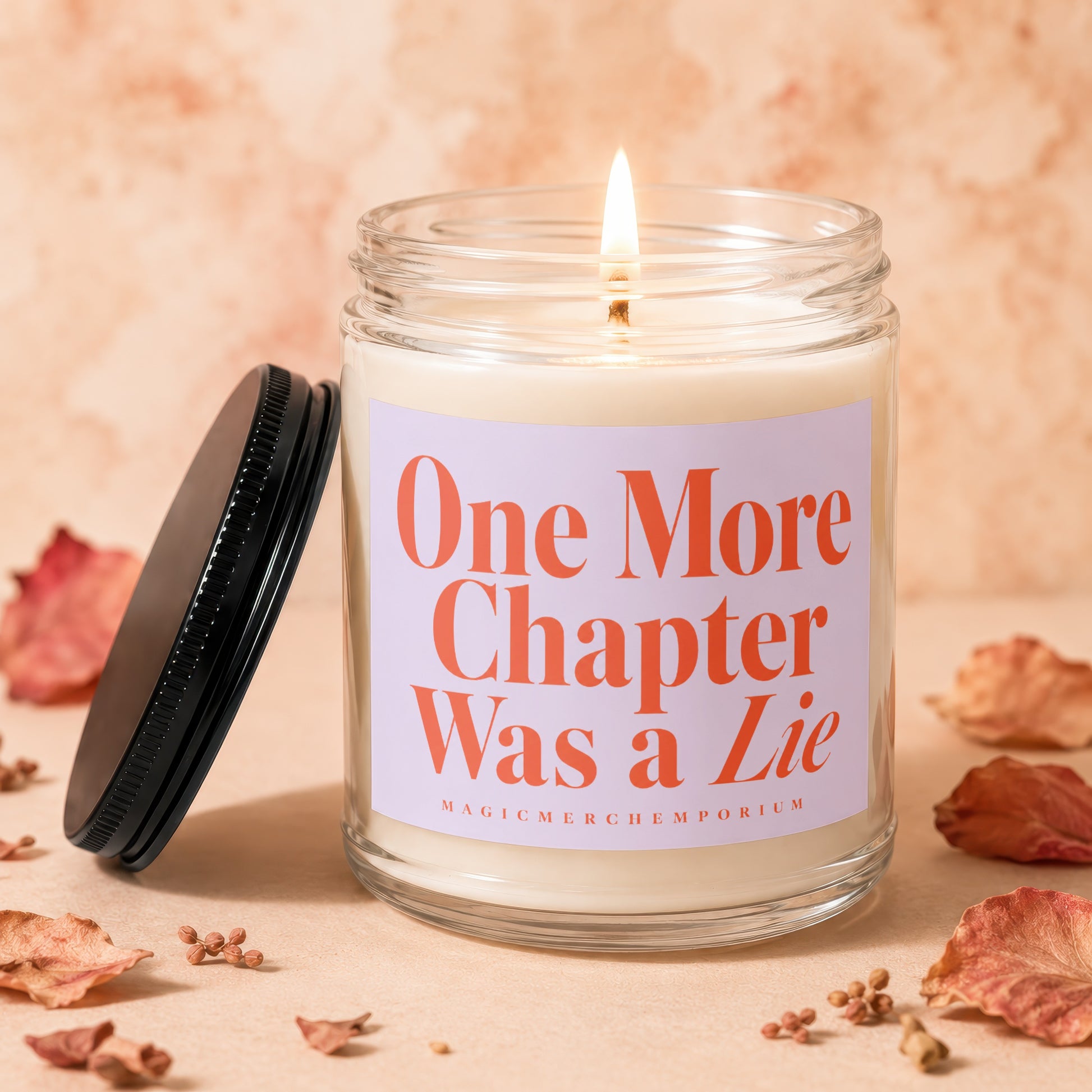 Candle with label "One More Chapter Was a Lie" and lit wick, surrounded by dried leaves.