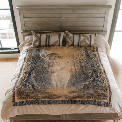a bed with a large, intricately designed blanket featuring a deer in a forest setting. The blanket is spread out on the bed, covering the entire surface.