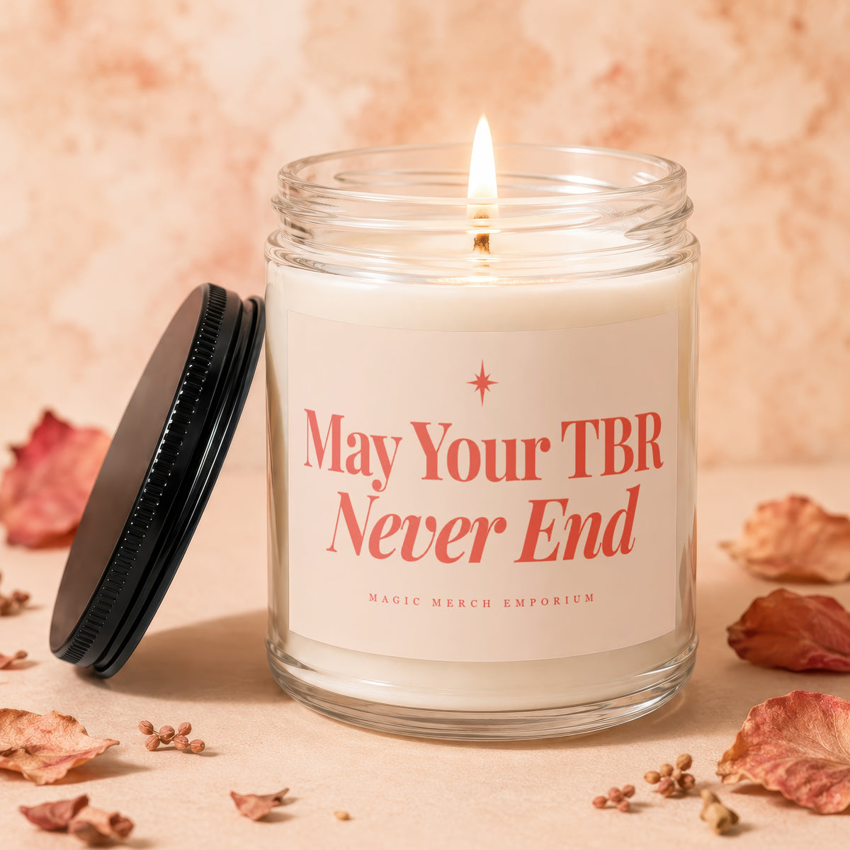 Glass candle with lit wick, "May Your TBR Never End" text, and black lid.