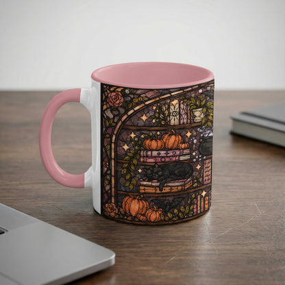 White mug with pink handle featuring a stained-glass design of a black cat and pumpkins.
