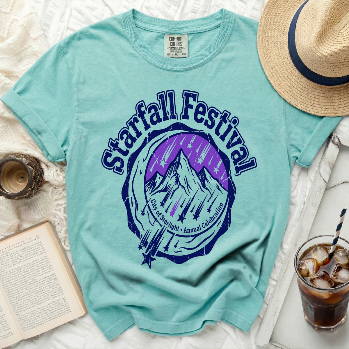 Teal t-shirt with Starfall Festival graphic of mountains and stars.