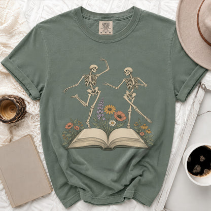 Green t-shirt with dancing skeletons on an open book with flowers.