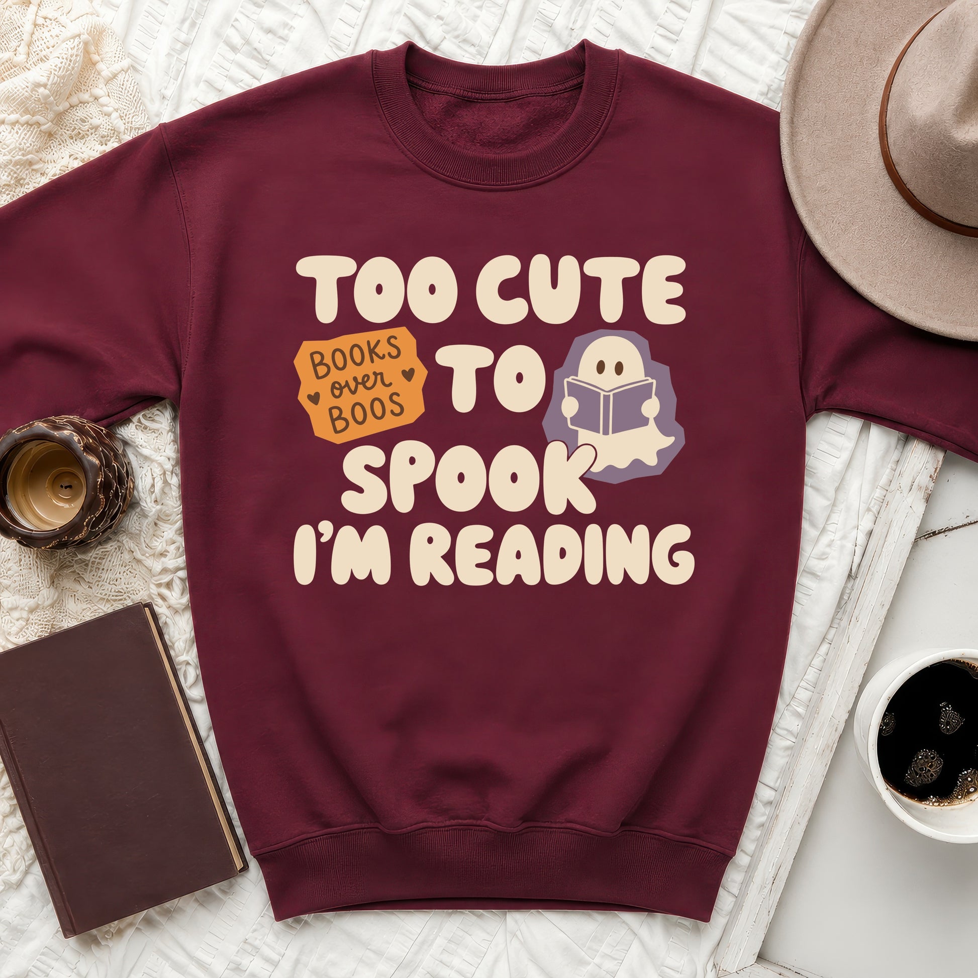 Maroon sweatshirt with "Too Cute To Spook I'm Reading" text and ghost graphic.