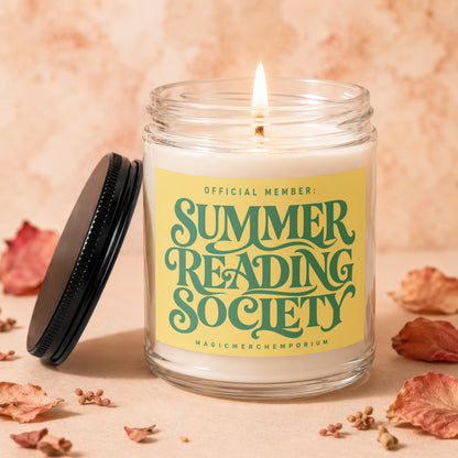 Lit candle in a glass jar with "Summer Reading Society" on a yellow label.