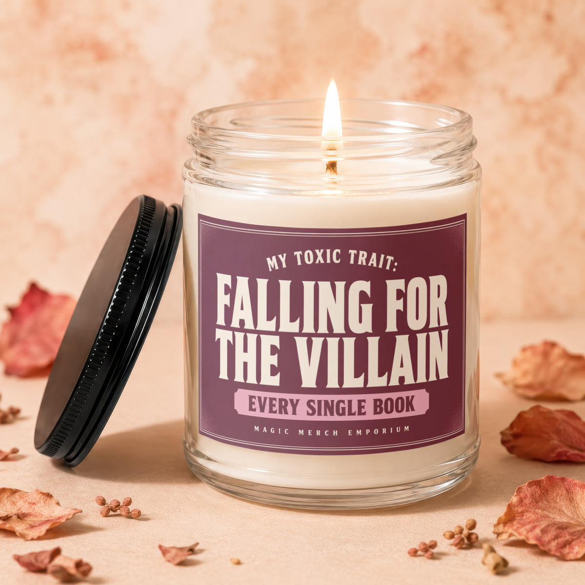 Candle with lit wick, lid off, reading "Falling For The Villain Every Single Book".