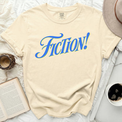 Cream Comfort Colors t-shirt with "FICTION!" in blue and yellow script.