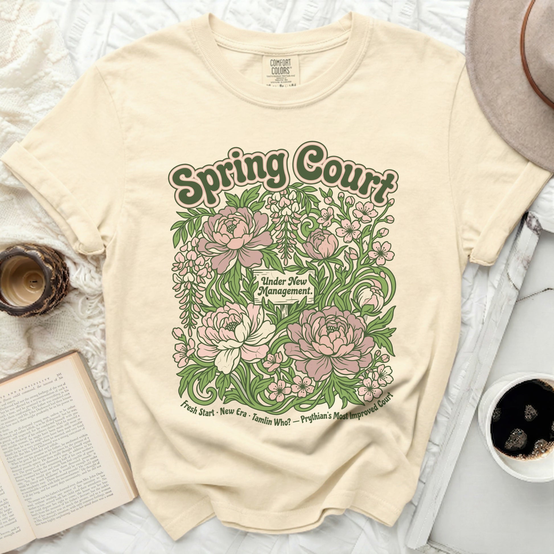 Cream t-shirt with "Spring Court Under New Management" floral graphic and text.