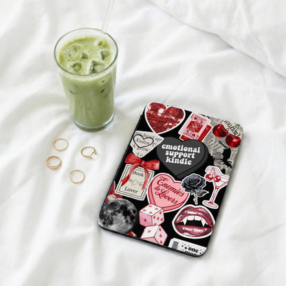 Black Kindle cover with "emotional support kindle" and various stickers, next to iced matcha drink.