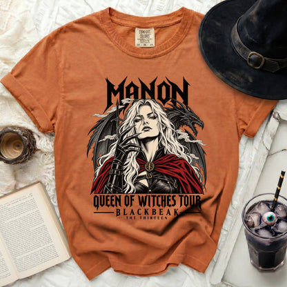 Orange t-shirt with "MANON QUEEN OF WITCHES TOUR BLACKBEAK THE THIRTEEN" graphic.