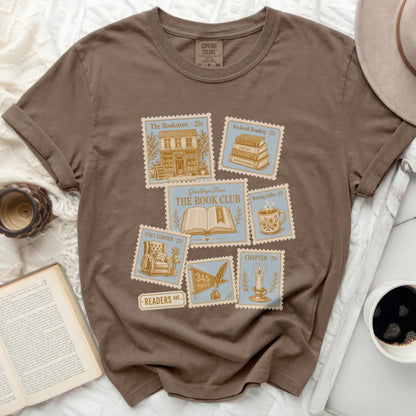 Brown t-shirt with vintage stamp graphics featuring books and coffee.