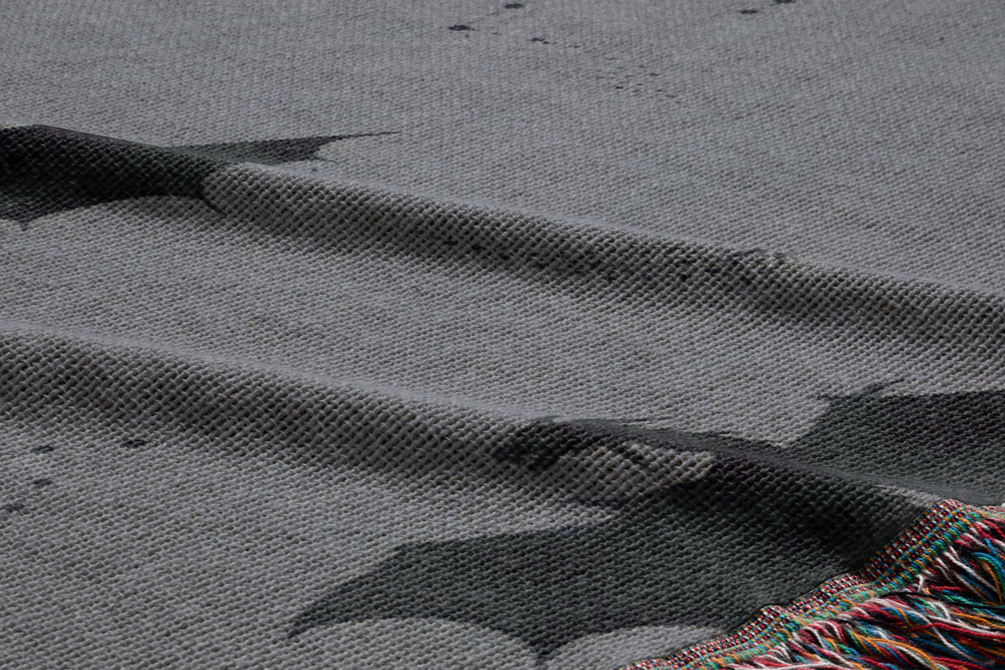 a close-up view of a textured fabric with a bat pattern, featuring a dark bat silhouette against a lighter background.