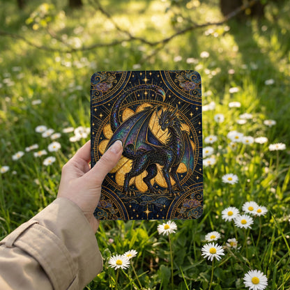 A hand holds a dark ereader displaying an ornate dragon illustration against a field of white daisies.