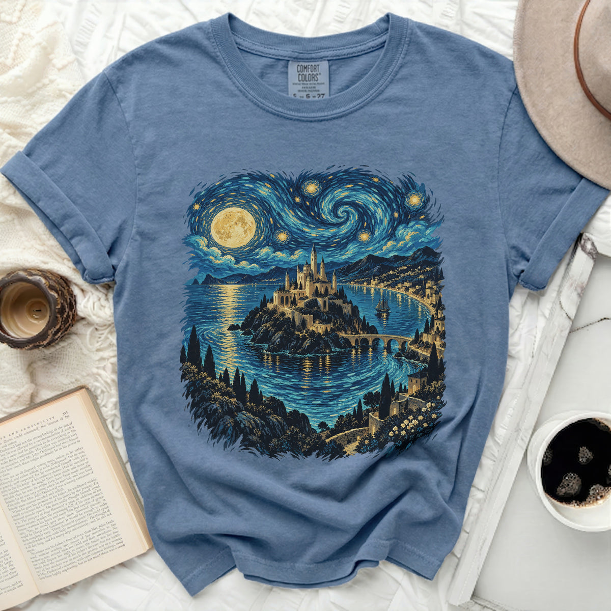 Blue t-shirt with a castle on an island under a swirling starry sky.