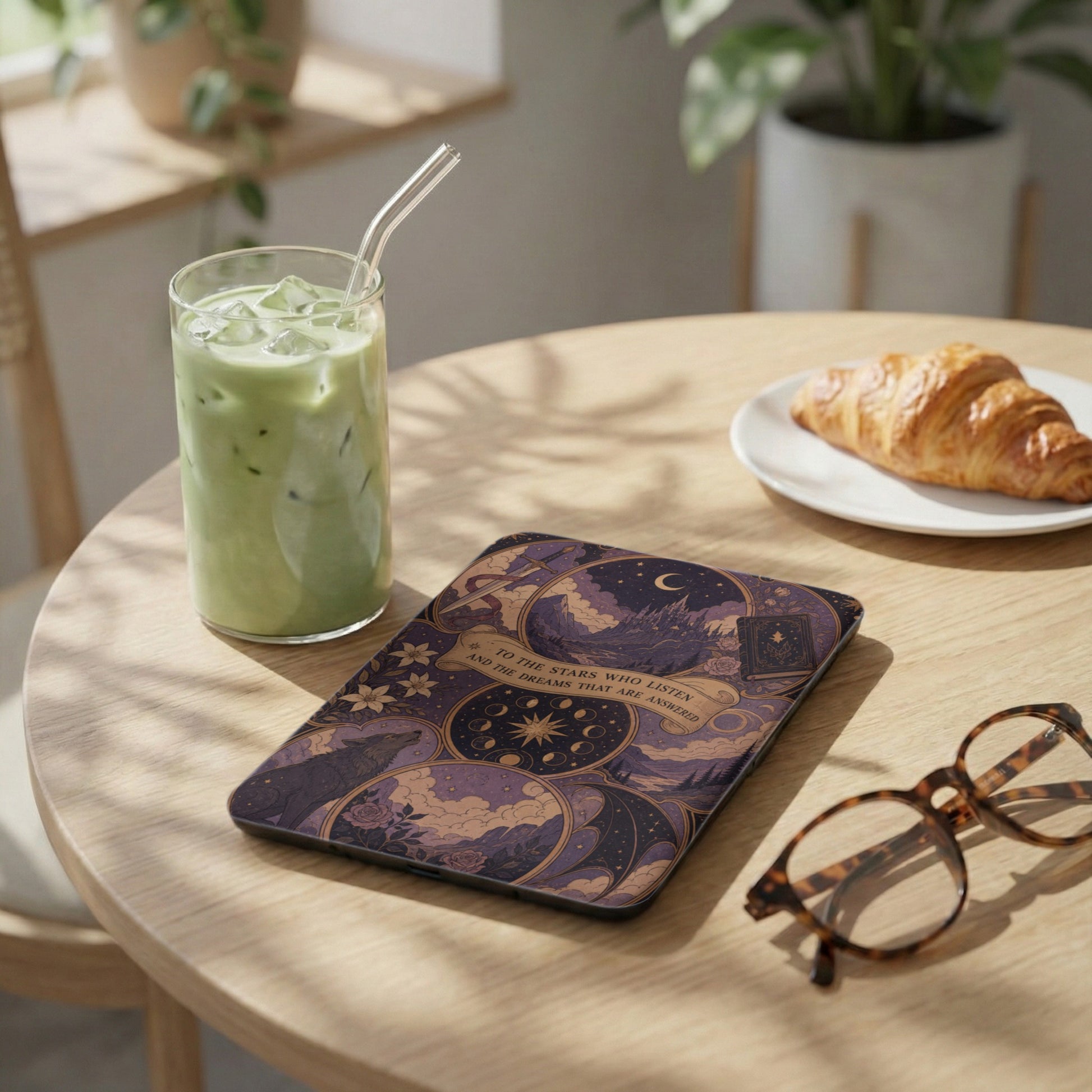 Tablet case with starry night and wolf design on wooden table with latte and croissant.