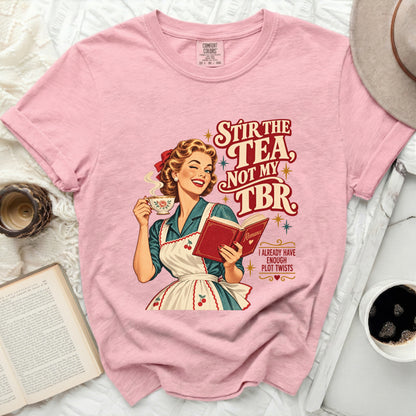 Pink t-shirt with a retro illustration of a woman holding tea and a book, text reads "Stir the tea, not my TBR".