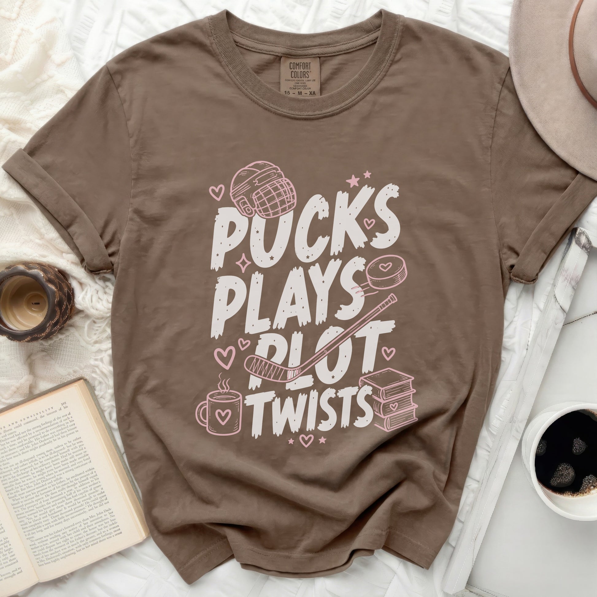 Brown t-shirt with "Pucks Plays Plot Twists" and hockey graphics.