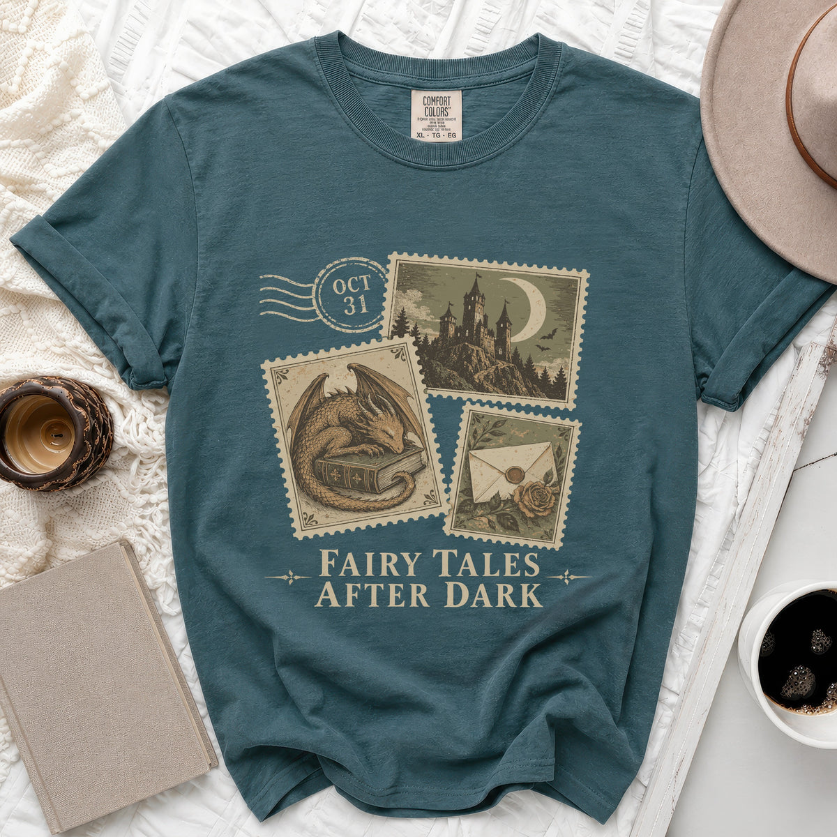 Teal t-shirt with "Fairy Tales After Dark" print featuring stamps of a dragon, castle, and envelope.
