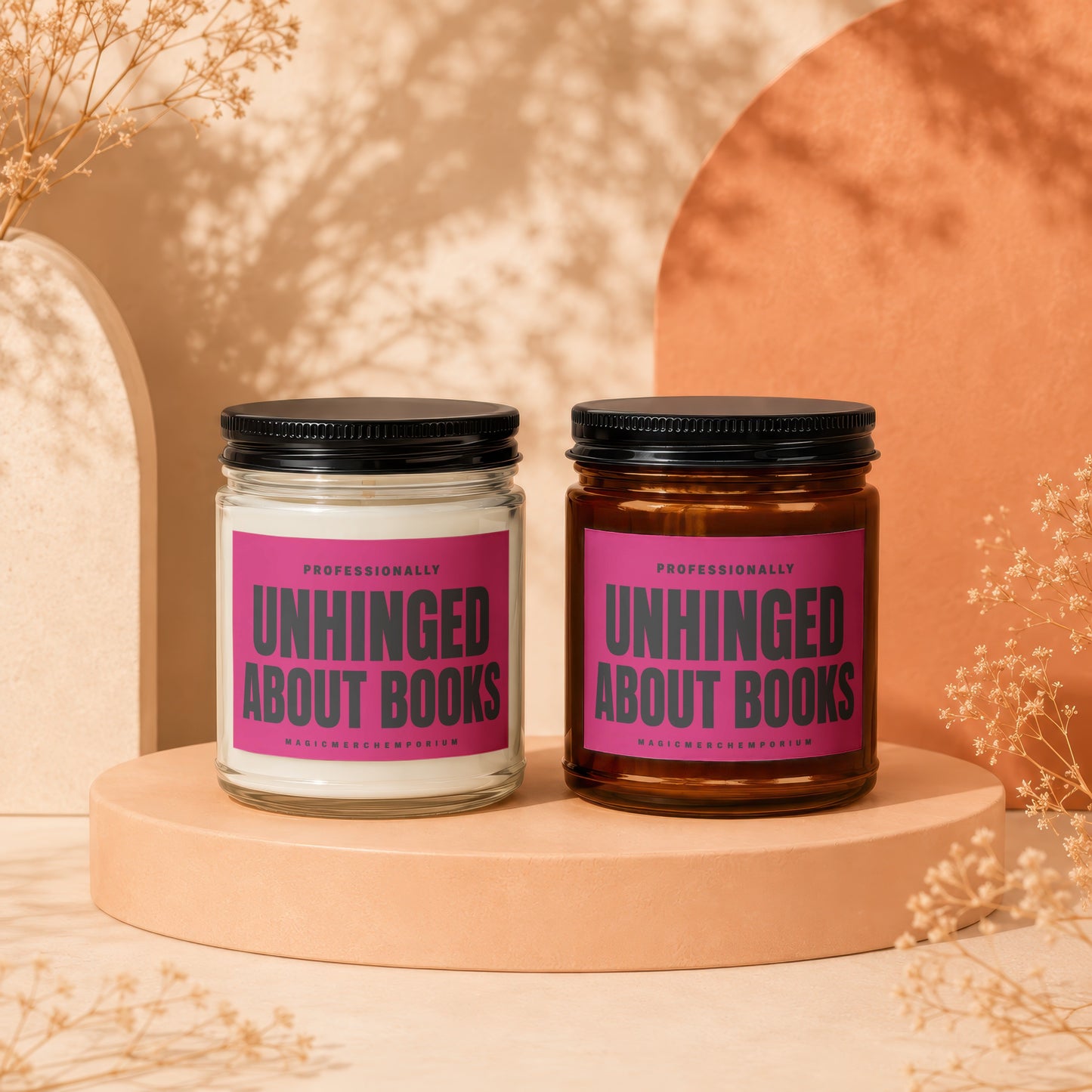 Two candles with pink labels that say "Unhinged About Books" and "MagicMerch Emporium".