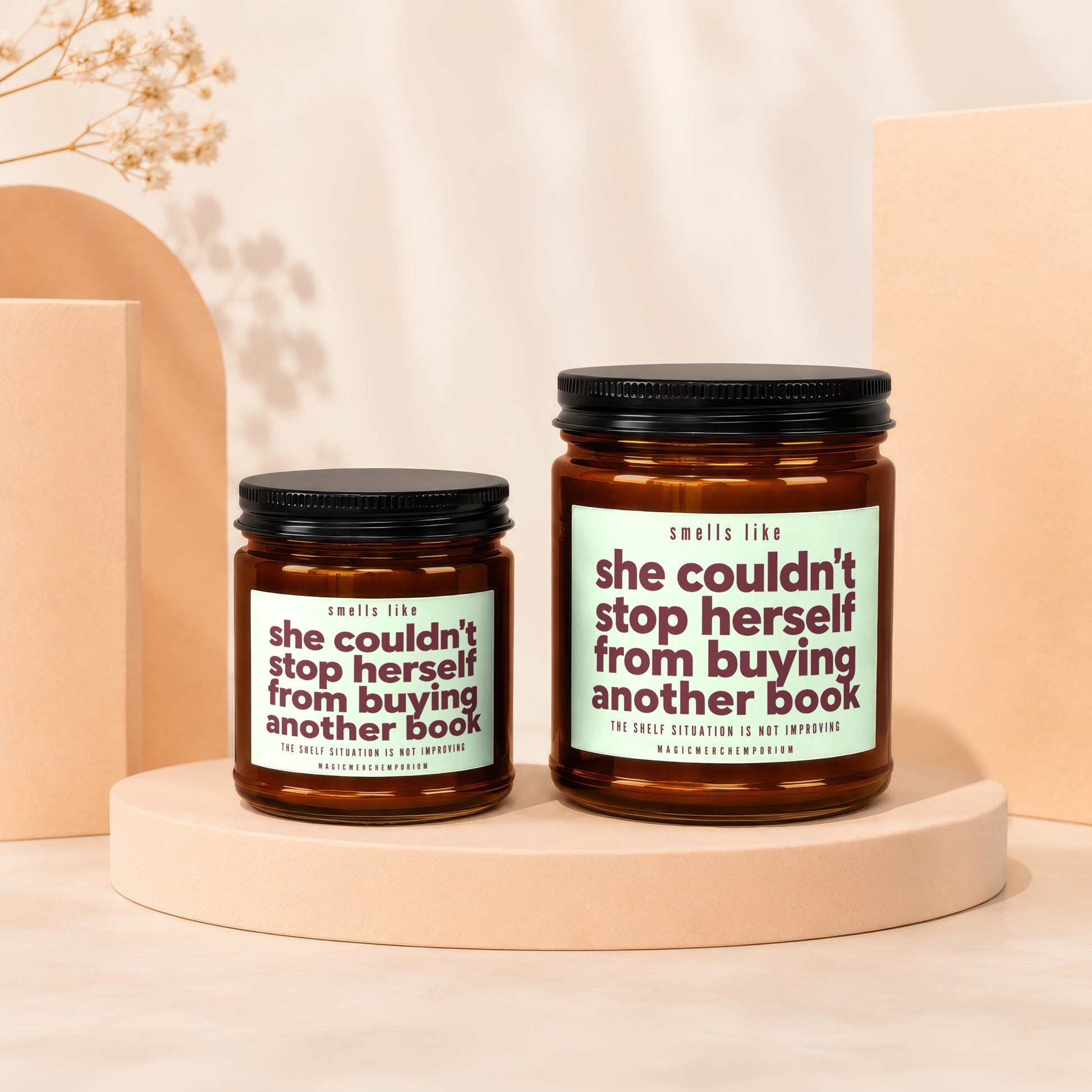 Two candles with labels reading "she couldn't stop herself from buying another book."