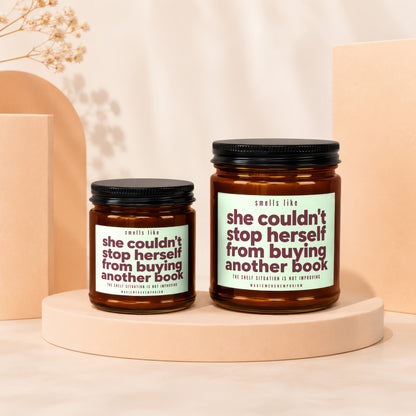 Two candles with labels reading "she couldn't stop herself from buying another book."