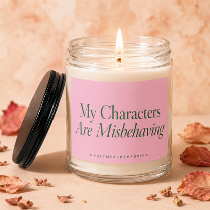 Candle with lit wick reading "My Characters Are Misbehaving" and "Magic Merch Emporium".