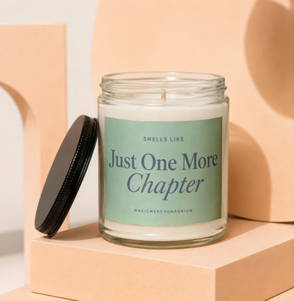 Glass candle with black lid, labeled with "Smells Like Just One More Chapter".