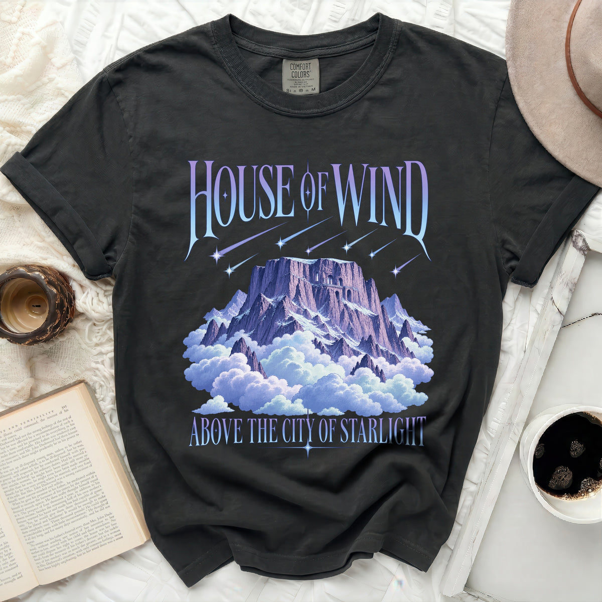Dark t-shirt with "House of Wind Above the City of Starlight" text and mountain graphic.