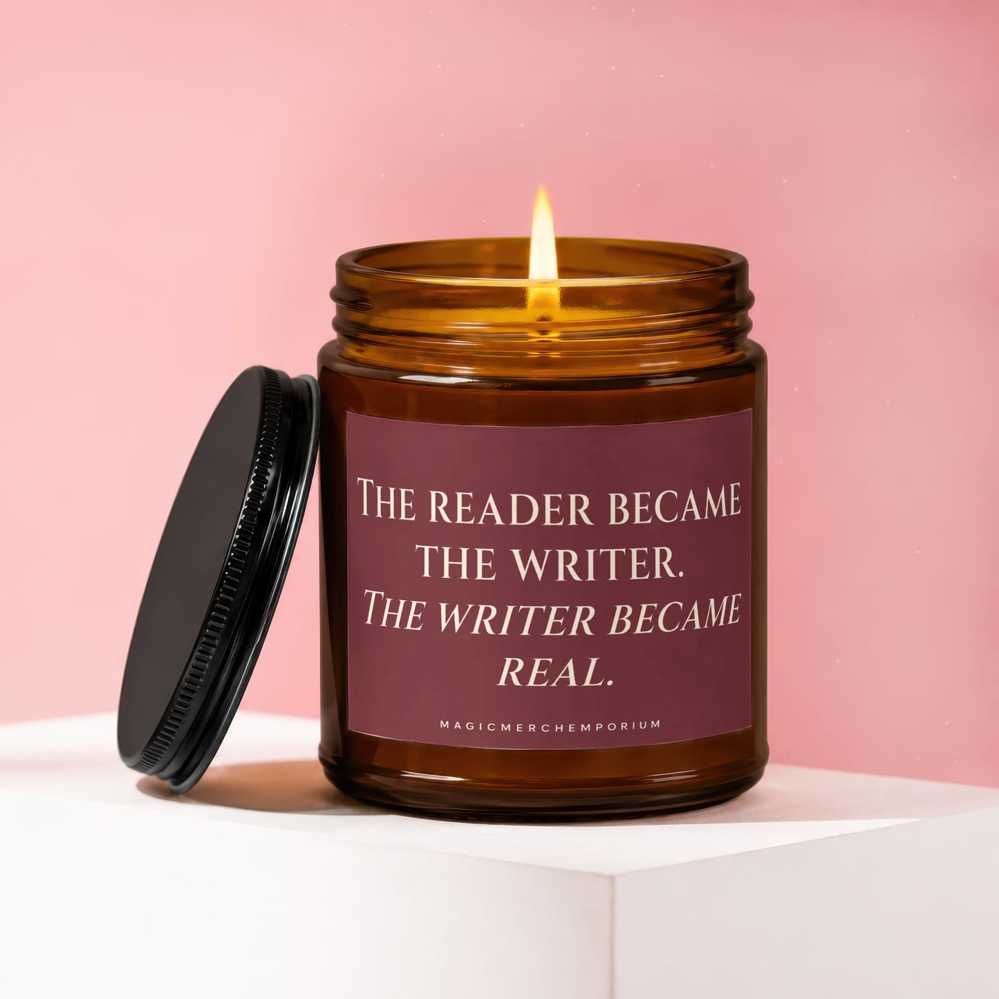 Amber jar candle with lit flame and text "The Reader Became The Writer. The Writer Became Real."