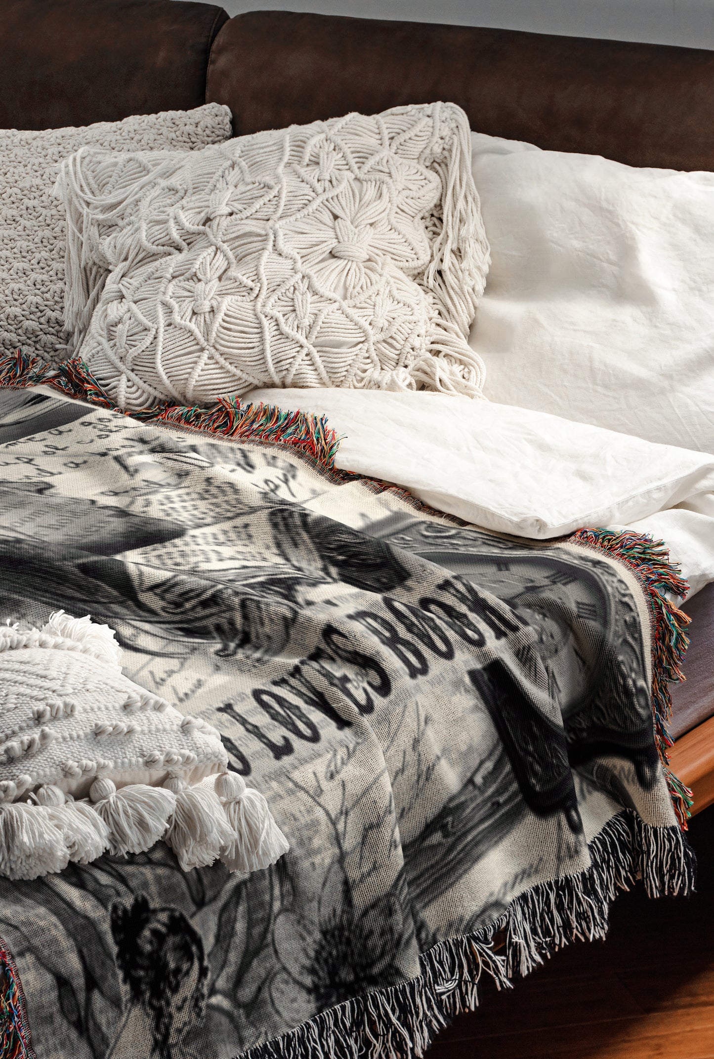 a cozy and inviting bedroom scene, featuring a bed with a white comforter and a decorative throw blanket with a black and white pattern. The bed is adorned with two white pillows and a white shawl, creating a warm and comfortable atmosphere.