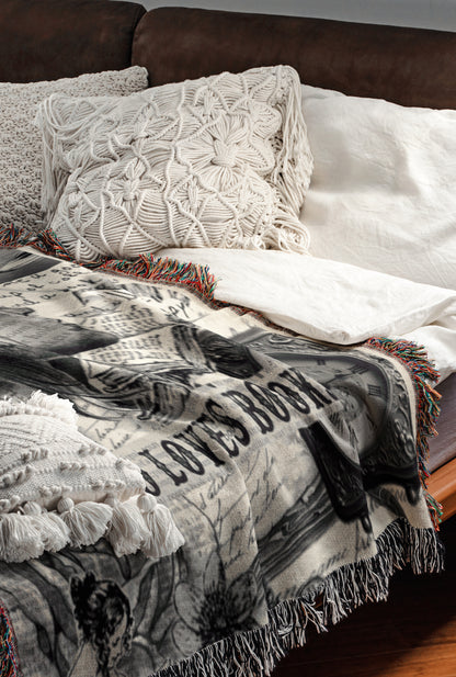 a cozy and inviting bedroom scene, featuring a bed with a white comforter and a decorative throw blanket with a black and white pattern. The bed is adorned with two white pillows and a white shawl, creating a warm and comfortable atmosphere.