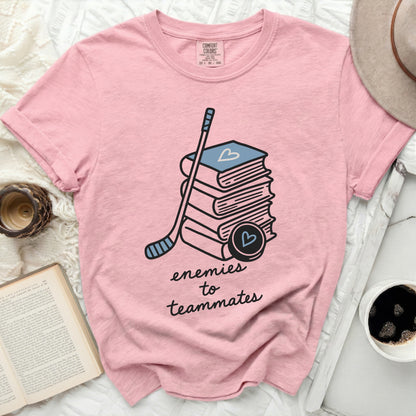 Pink t-shirt with books, hockey stick, and puck; text "enemies to teammates."