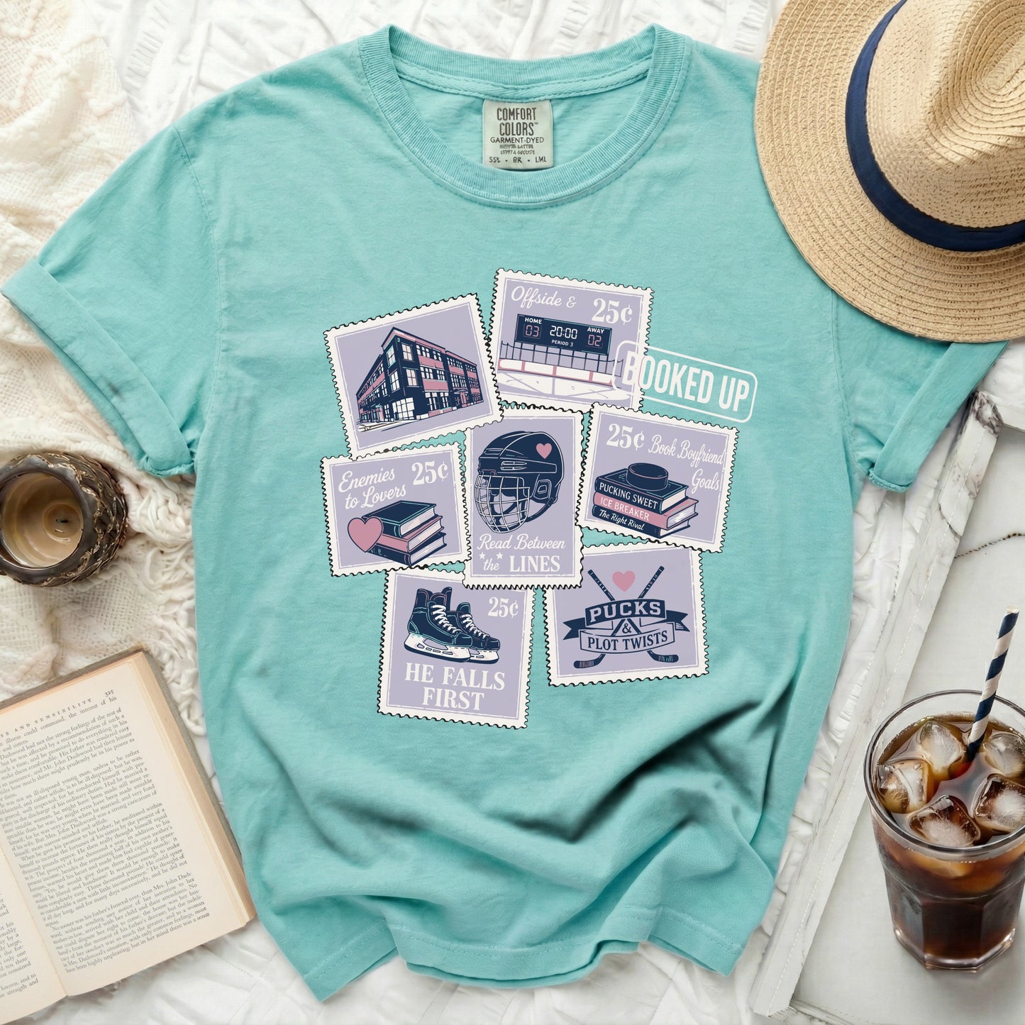 Teal t-shirt with stamp designs featuring books, hockey, and reading puns.