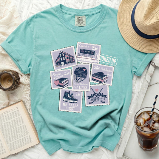Teal t-shirt with stamp designs featuring books, hockey, and reading puns.