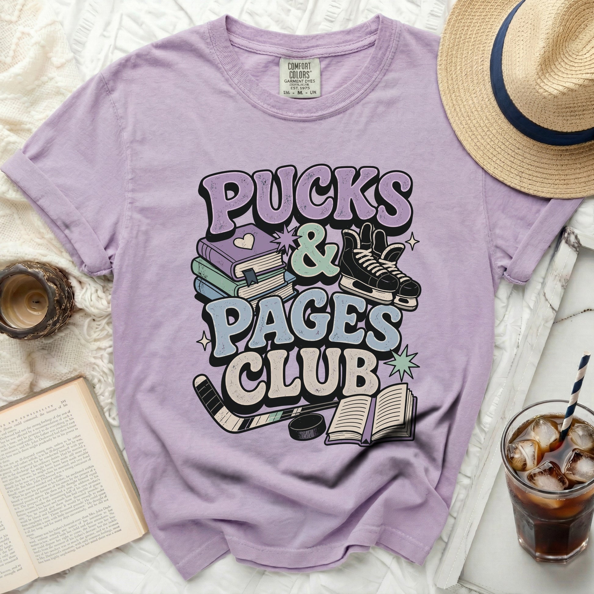 Purple t-shirt with "Pucks & Pages Club" text and hockey imagery.