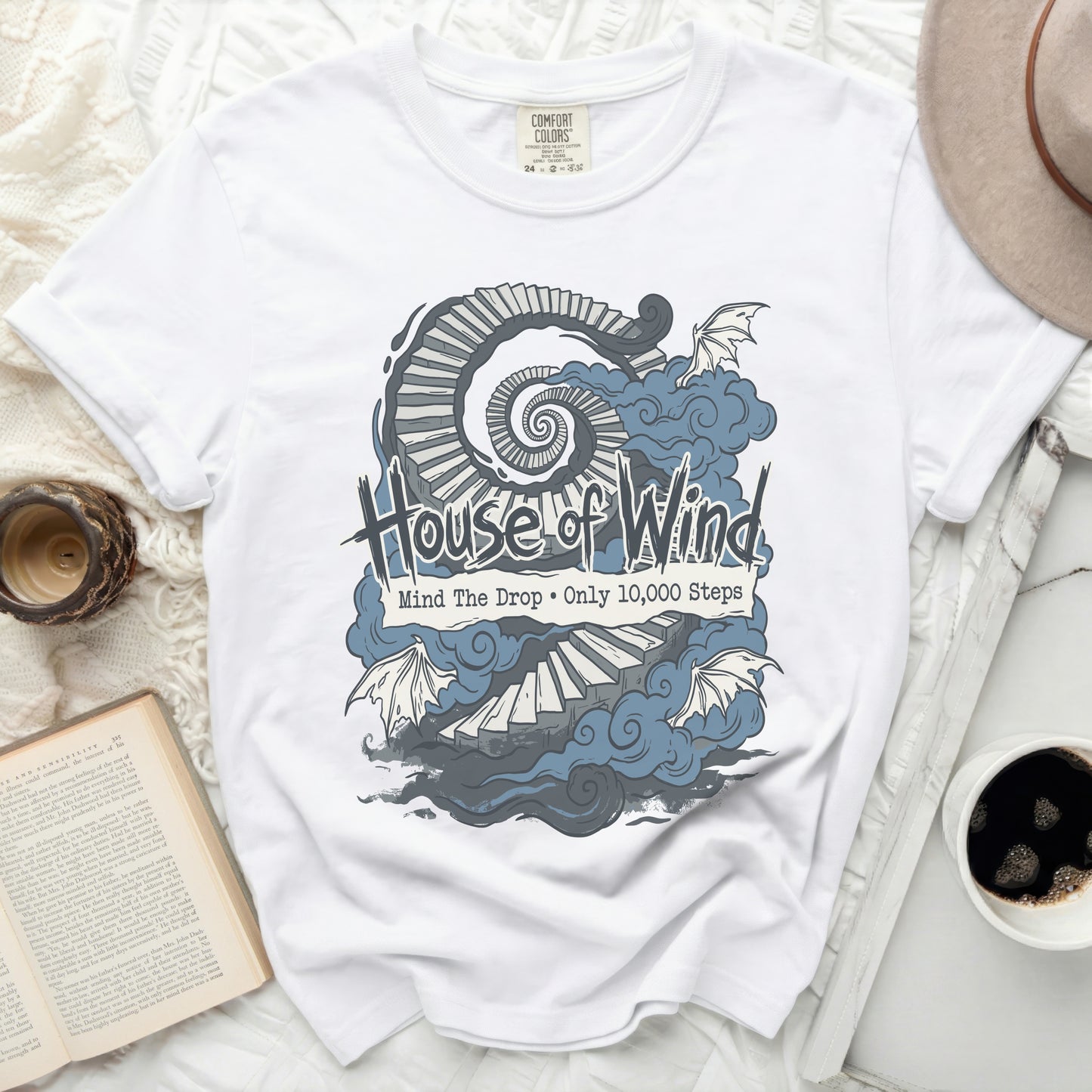 White t-shirt with "House of Wind, Mind The Drop • Only 10,000 Steps" graphic.