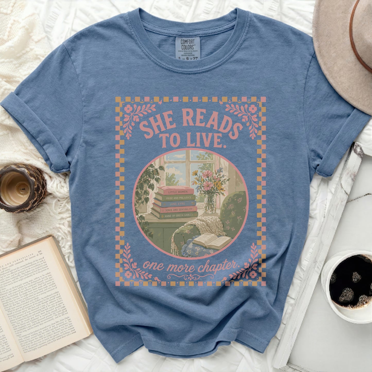 Blue t-shirt with "SHE READS TO LIVE. one more chapter." text and book graphic.