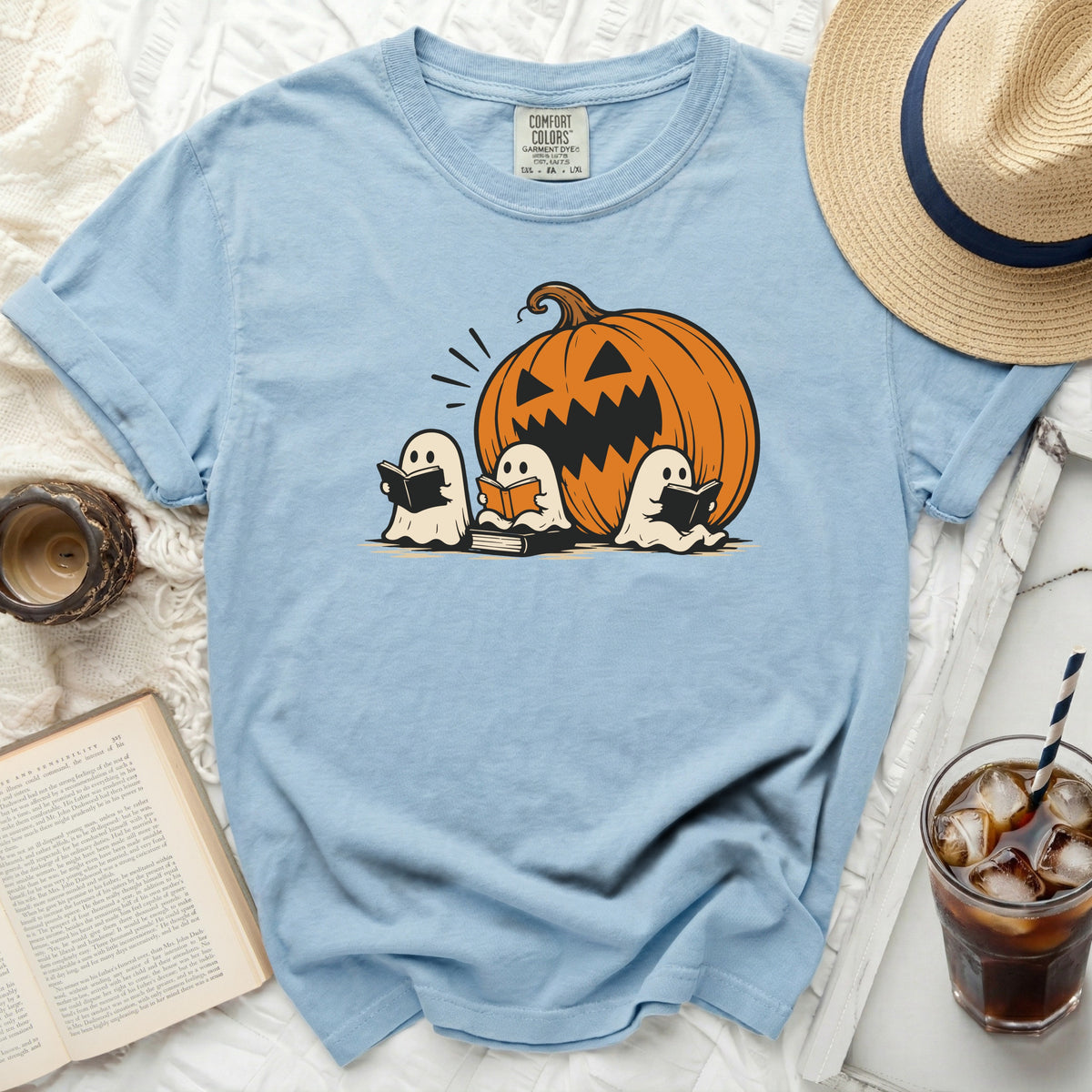 Light blue t-shirt with a graphic of three ghosts reading books and a jack-o'-lantern.