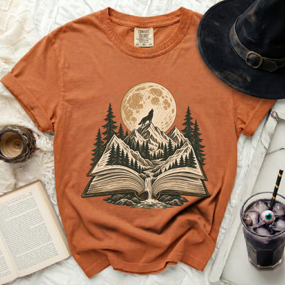 Orange t-shirt with a book scene featuring a wolf under a full moon.