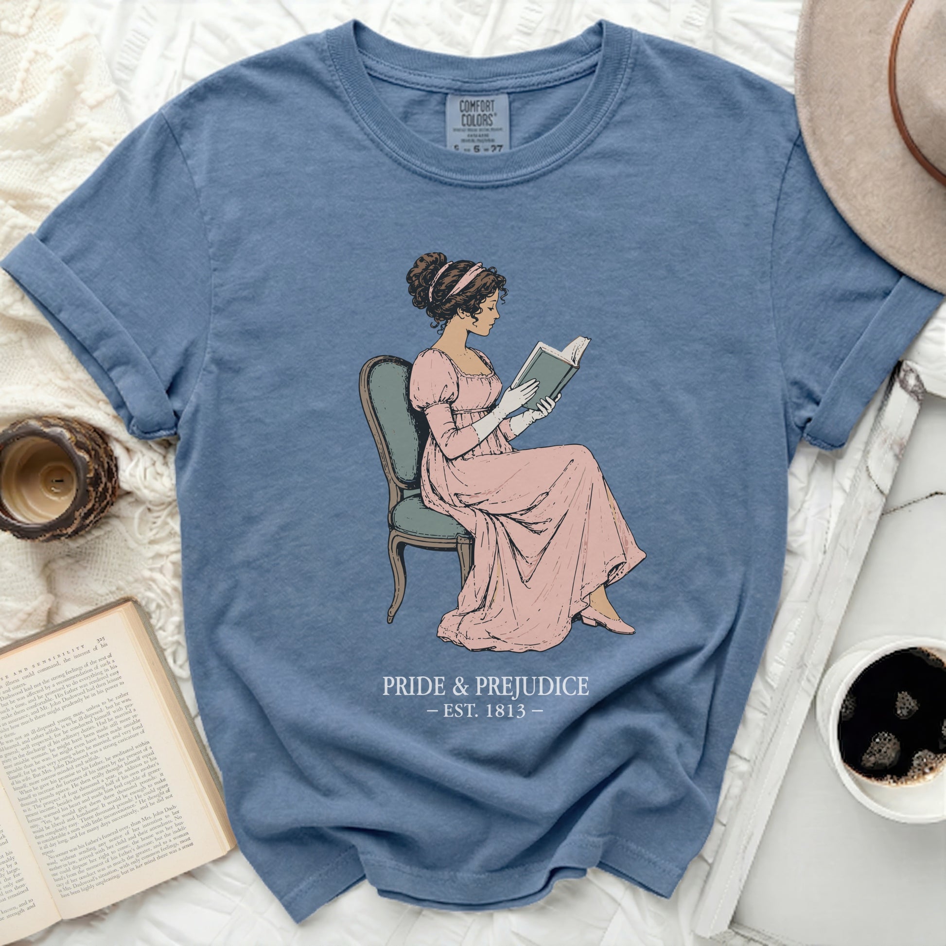 Blue t-shirt with "Pride & Prejudice Est. 1813" and a drawing of a woman reading.