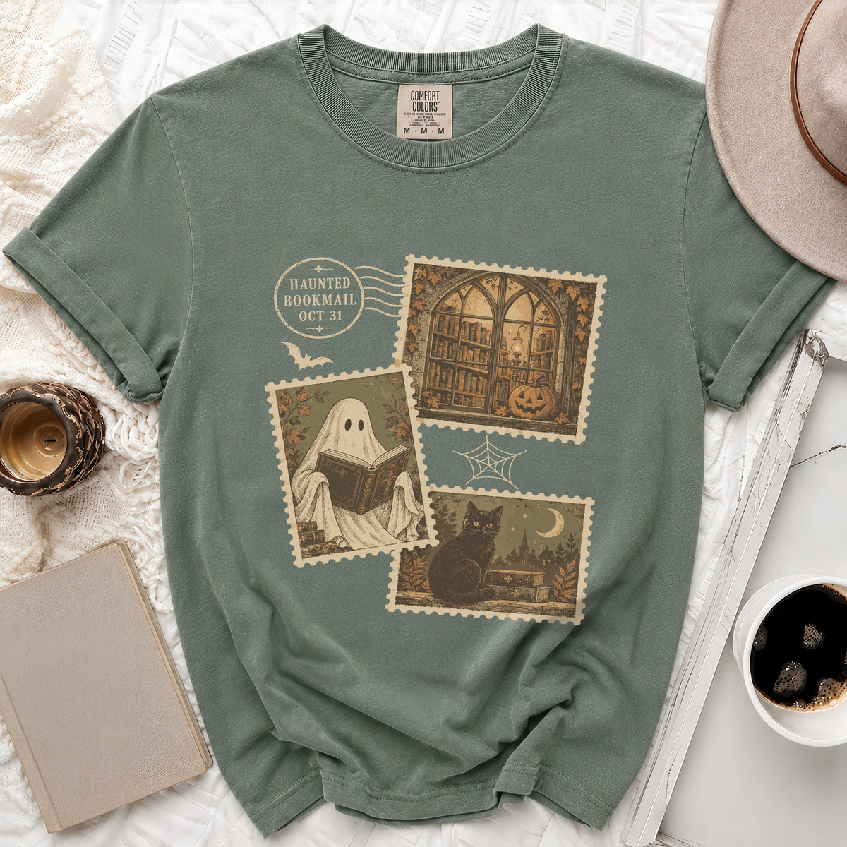 Green t-shirt with Halloween-themed postage stamps: ghost reading, library, black cat, and pumpkin.
