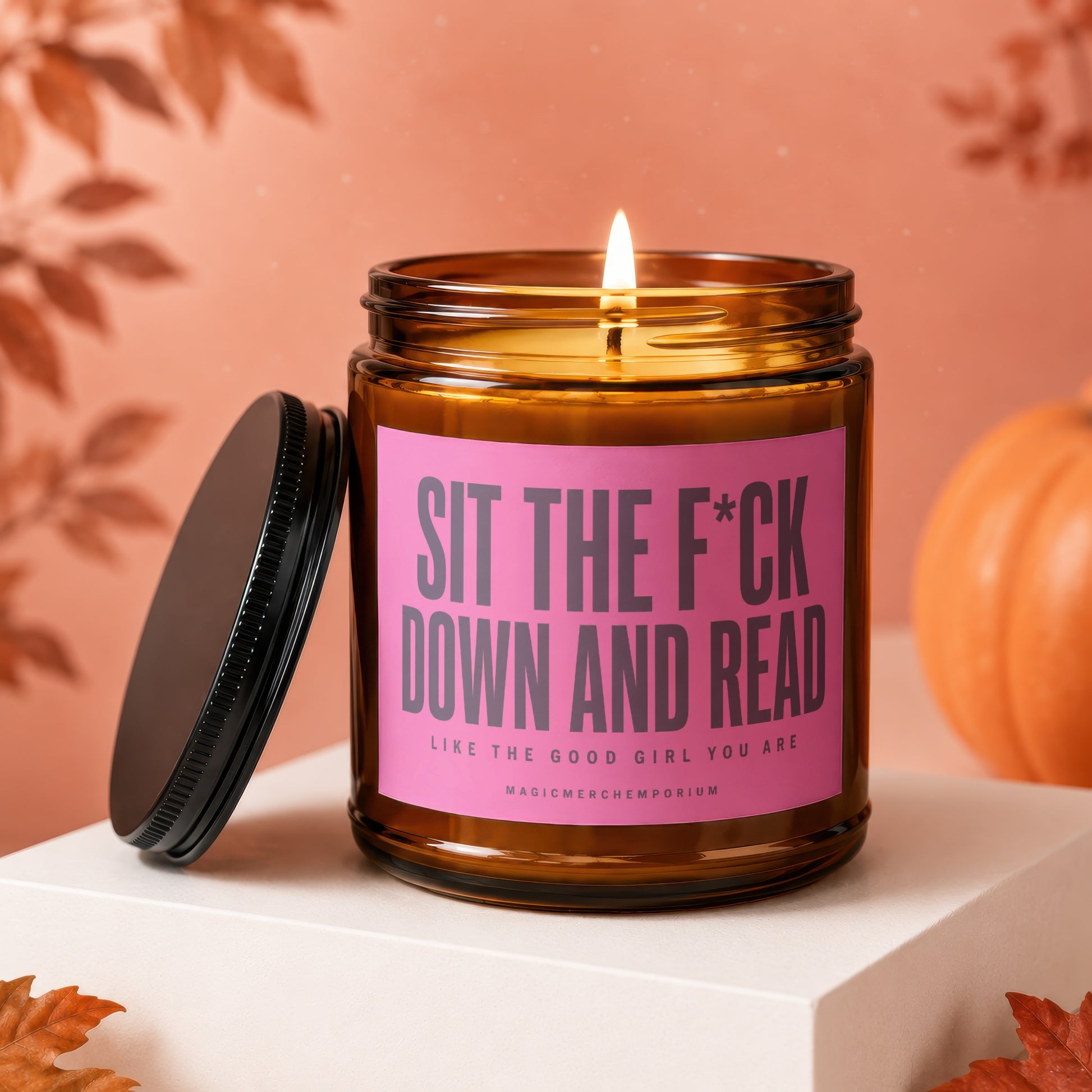 Amber candle with a pink label reading "sit the f*ck down and read".