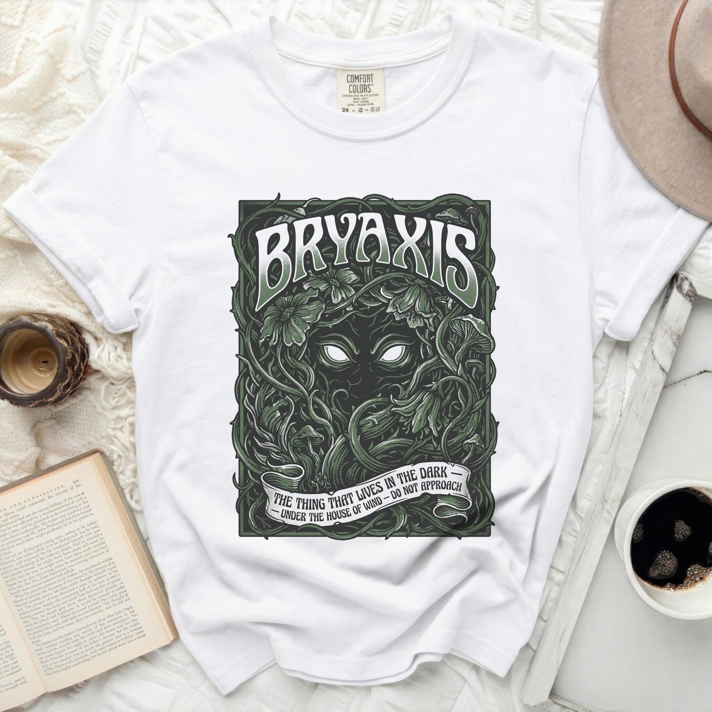White t-shirt with "BRYAXIS" and creature art, "THE THING THAT LIVES IN THE DARK" text.