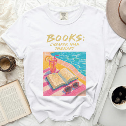 White t-shirt with "BOOKS: CHEAPER THAN THERAPY" graphic and poolside illustration.